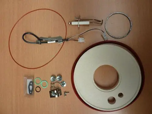 Wartungssatz für Remeha, bestehend aus verschiedenen Bauteilen: Kabel, Dichtungen, Schrauben, ein Gasket, und ein runder Gehäusedeckel.